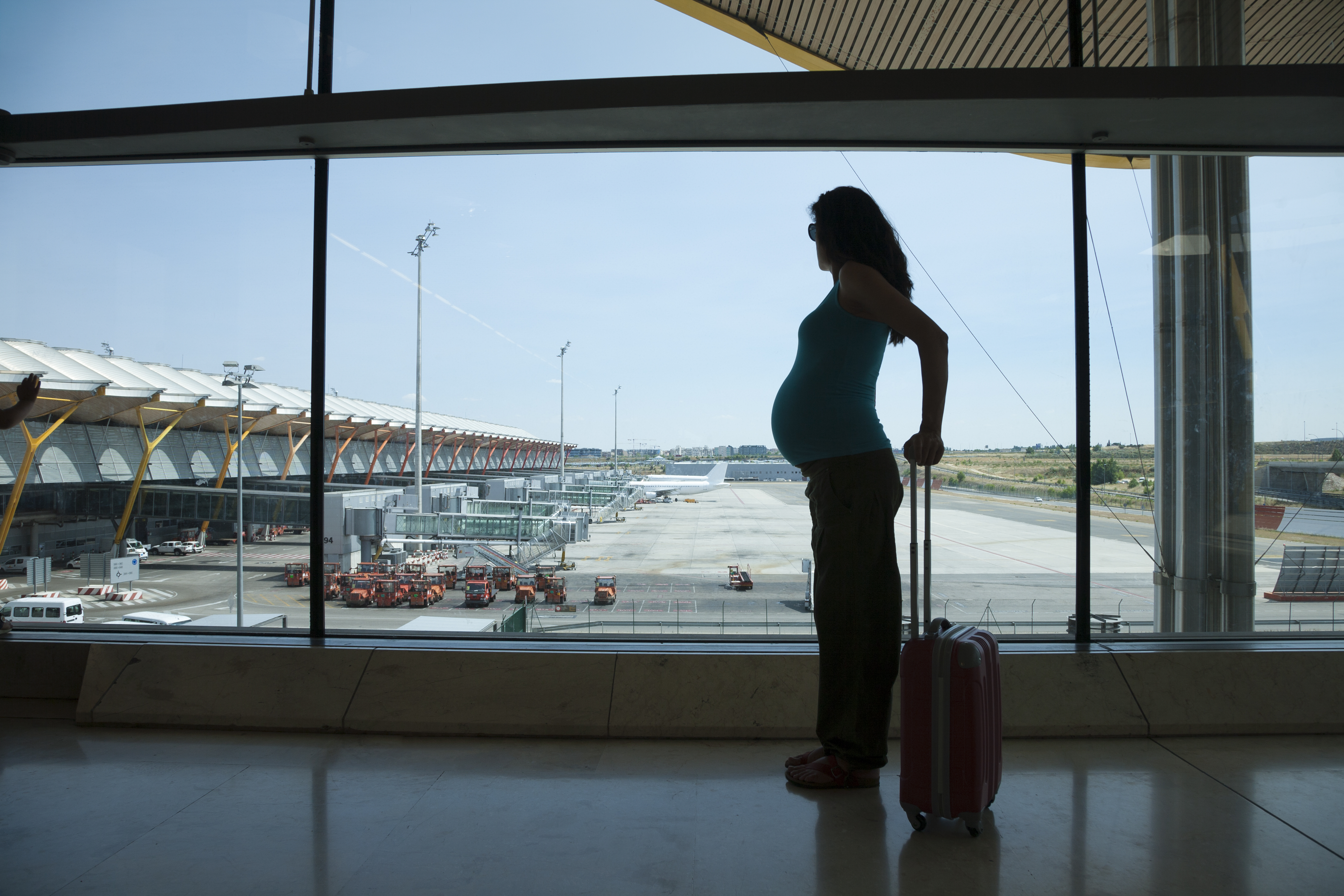 woman pregnant silhouette waiting to fly in airport hall